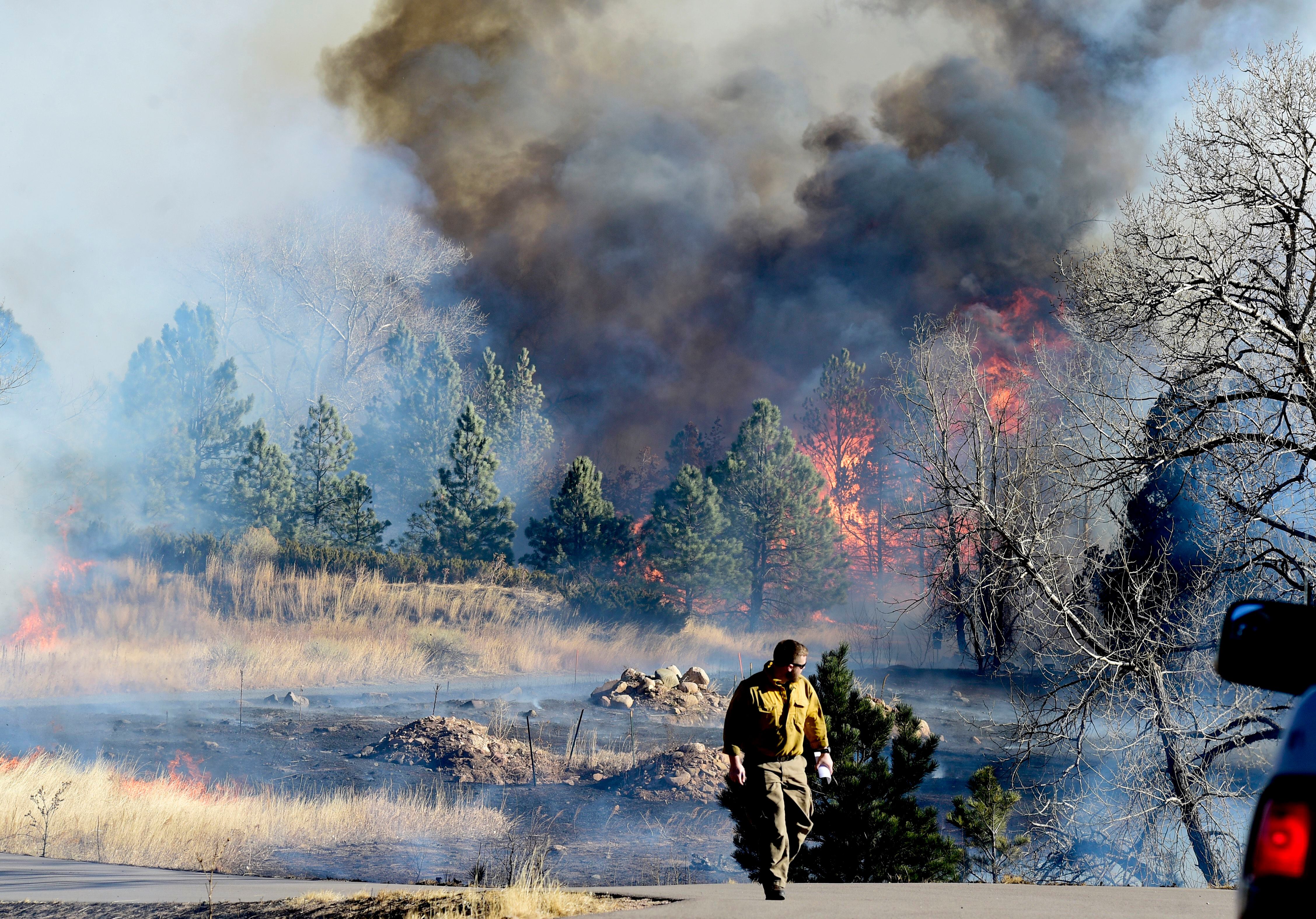 (Cliff Grassmick | Daily Camera via AP) A firefighter walks up a road near a home at Middle Fork Road and Foothills Highway north of Boulder, Colo., on Thursday, Dec. 30, 2021.