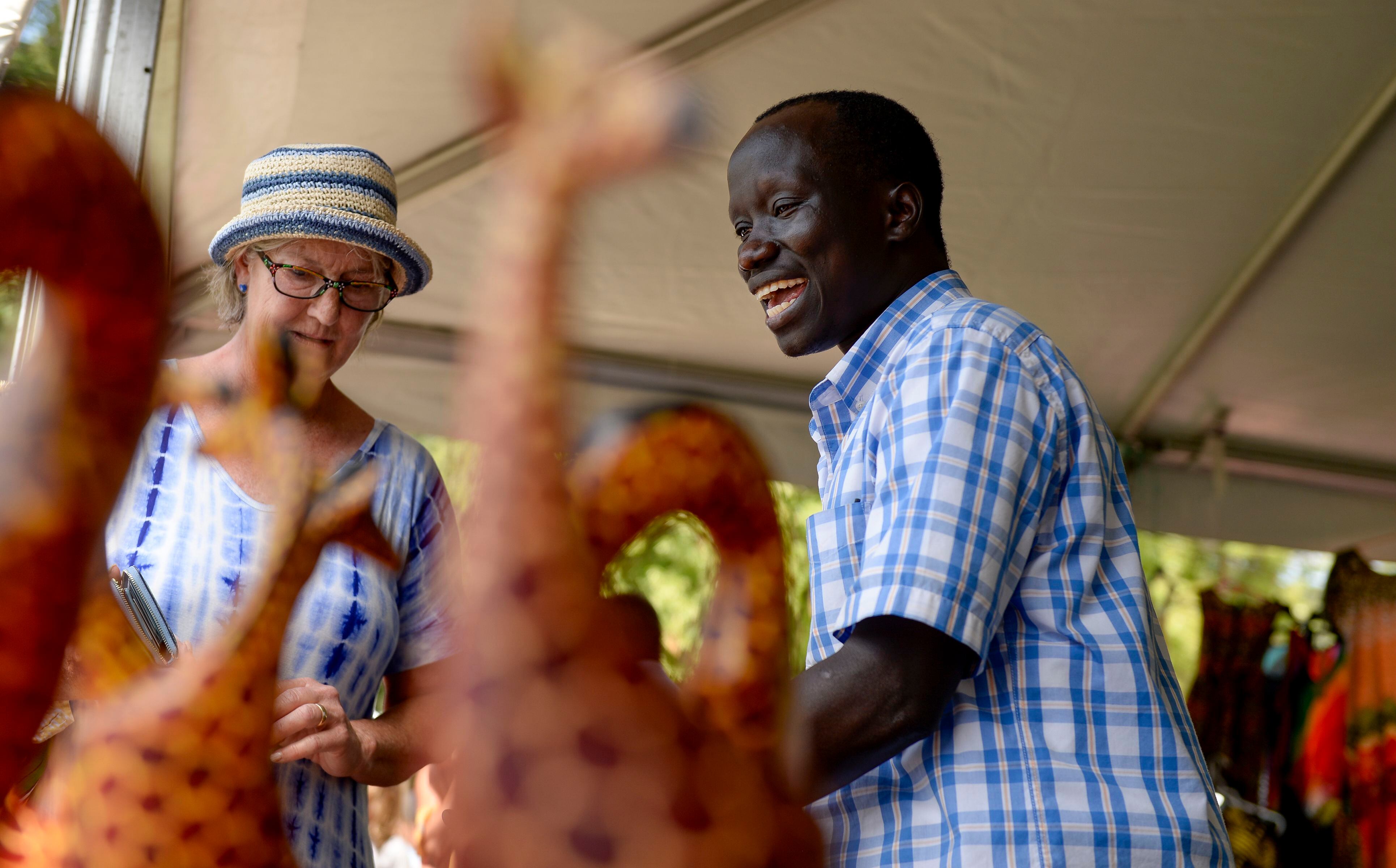 (Leah Hogsten | The Salt Lake Tribune) Dominic Raimondo, right, sells an beaded bowl to Betsy Carson de Avila during the 4th Annual African Festival sponsored by the United Africans of Utah, Saturday, July 27, 2019 at Liberty Park. The African Festival promotes African tradition, culture and heritage through the arts, food fashion, music and dance. The Dominic Raimondo Foundation raises money for South Sudan refugees living in a refugee camp in Kenya.