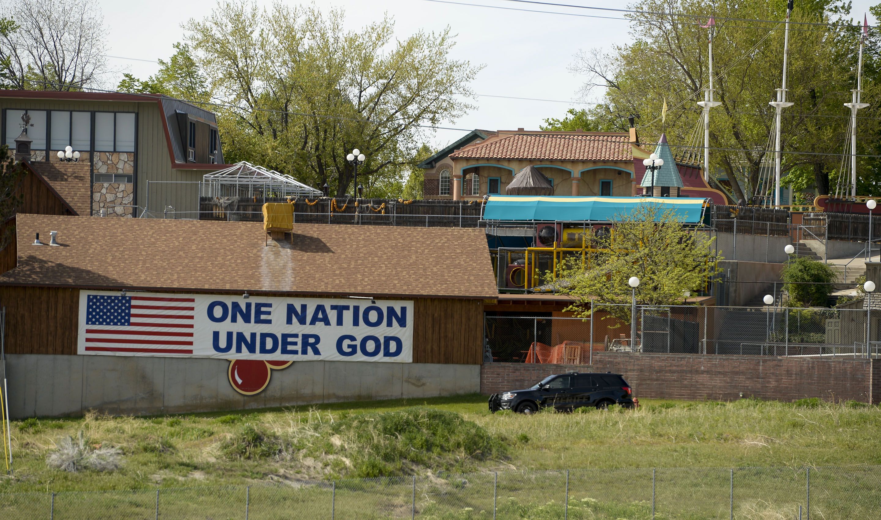 (Leah Hogsten | The Salt Lake Tribune) Cherries, from the Cherry Hill water park can barely be seen under a giant banner that reads, "One Nation Under God" in Farmington, April 29, 2020.