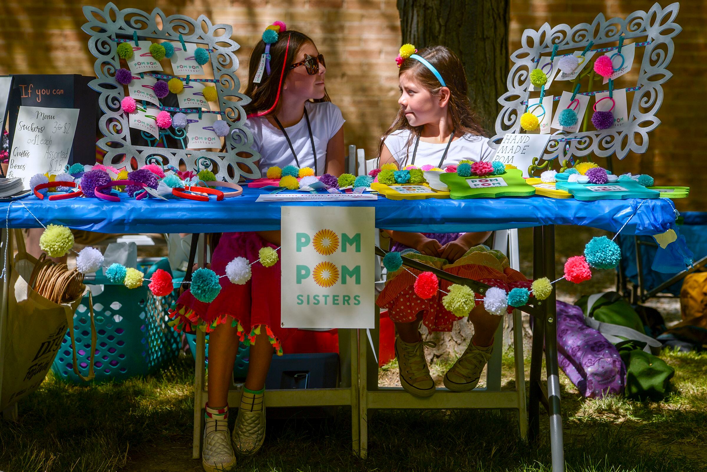 (Leah Hogsten | The Salt Lake Tribune) l-r The Pom Pom sisters Evi and Syrri Bateman peddle hair barrettes, headbands, picture frames and ponytail holders decorated with pom poms at the Craft Lake City DIY Festival Kid Row, where children 14 and under make and sell their products. Craft Lake CityÕs DIY Festival is UtahÕs largest local, three day arts festival with over 300 artisans, DIY engineers, vintage vendors and craft food creators.