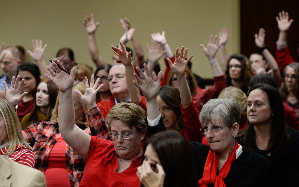 (Francisco Kjolseth | The Salt Lake Tribune) Teachers in red with buttons that read #red for ed, wave their hands in support of comments made for education at the tax reform task force has what may be its final meeting at the Utah Capitol on Monday, Nov. 25, 2019, with teachers turning out in large numbers to oppose any weakening of guarantee for public ed funding.