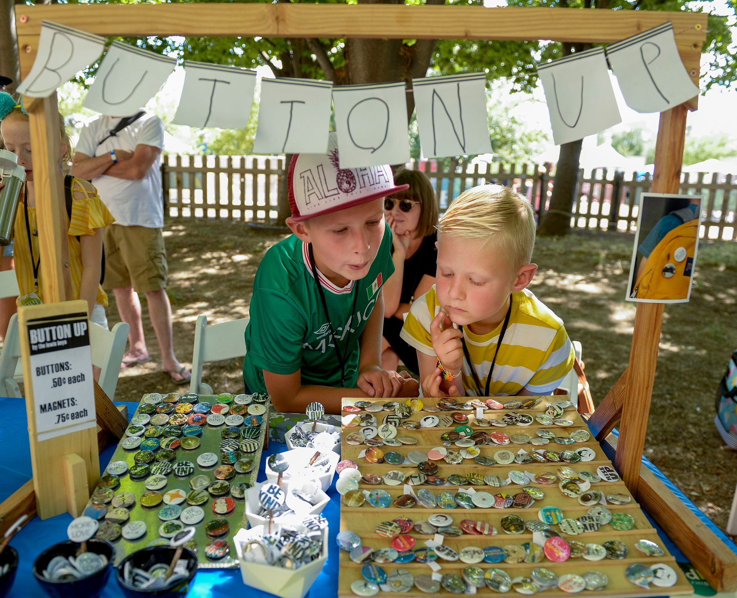 (Leah Hogsten | The Salt Lake Tribune) l-r Brothers Simon Lewis, 9, and Elliot Lewis, 7, sell art buttons at their Button Up booth with the mother, Lisa Lewis behind them at the Craft Lake City DIY Festival Kid Row, where children 14 and under make and sell their products. Craft Lake CityÕs DIY Festival is UtahÕs largest local, three day arts festival with over 300 artisans, DIY engineers, vintage vendors and craft food creators.