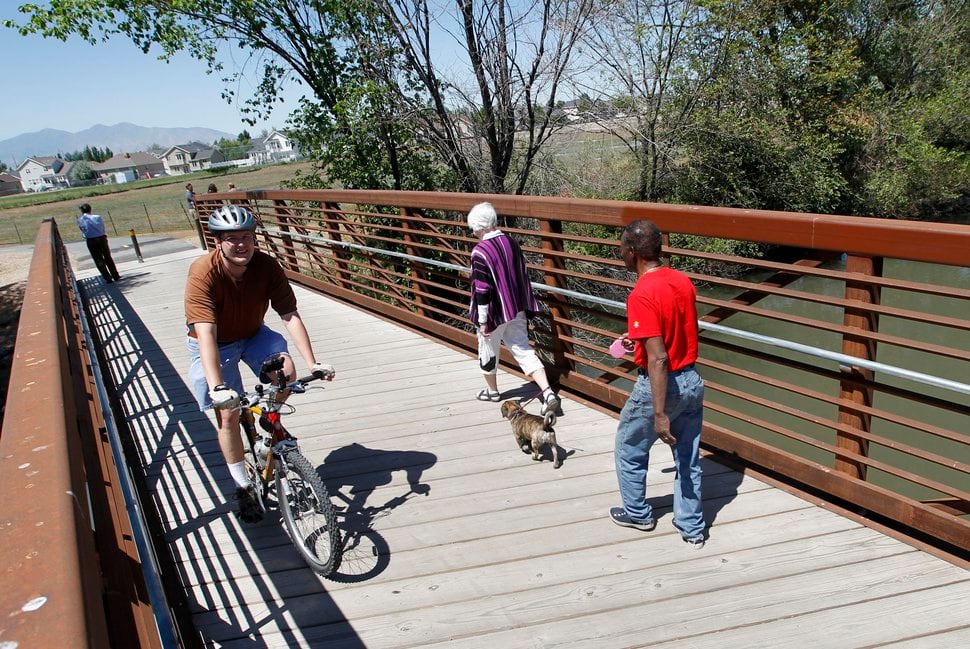 (Al Hartmann | Tribune file photo) Bicyclists and walkers cross the Jordan RIver on a bridge at 1800 North Redwood Road to access one of the last sections of the Jordan River Parkway Trail.