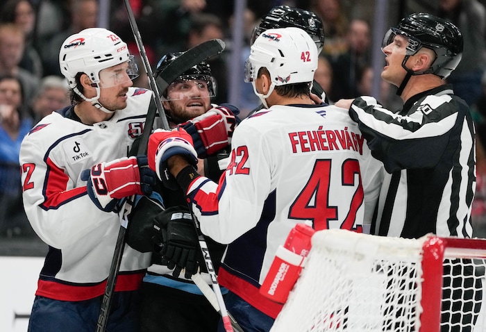 (Francisco Kjolseth  | The Salt Lake Tribune) Utah Hockey Club center Alexander Kerfoot (15) is grabbed by Washington Capitols players after knocking off the helmet of their goalie during an NHL hockey game at the Delta Center in Salt Lake City on Monday, Nov. 18, 2024.