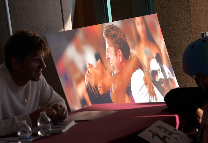 (Francisco Kjolseth  | The Salt Lake Tribune) Hunter Woodhall signs autographs for patients at Shriners Children’s Hospital alongside his wife Tara Davis-Woodhall, both gold medalists in the Paris 2024 Games, on Wednesday, Sept. 18, 2024. At right is a photograph taken when Tara won her gold medal. 