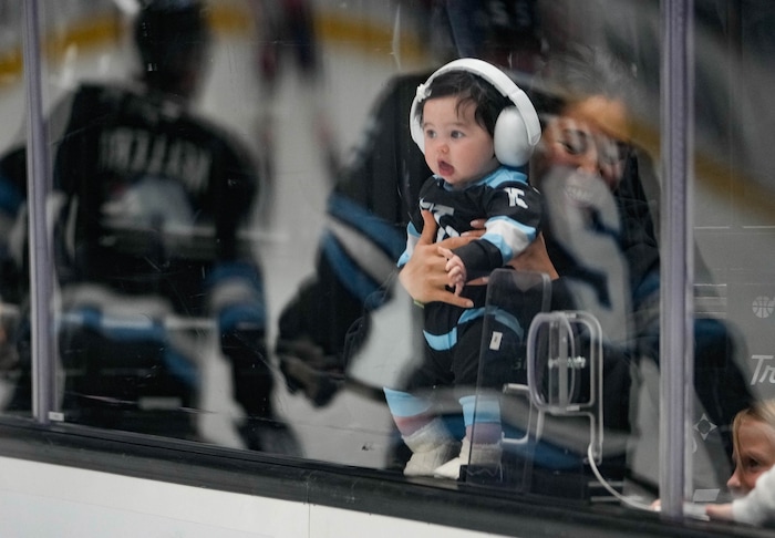 (Francisco Kjolseth  | The Salt Lake Tribune) Marissa Kerfoot holds her daughter Carrera as they watch the Utah Hockey Club warm up before their game against the Washington Capitols during an NHL hockey game at the Delta Center in Salt Lake City on Monday, Nov. 18, 2024.