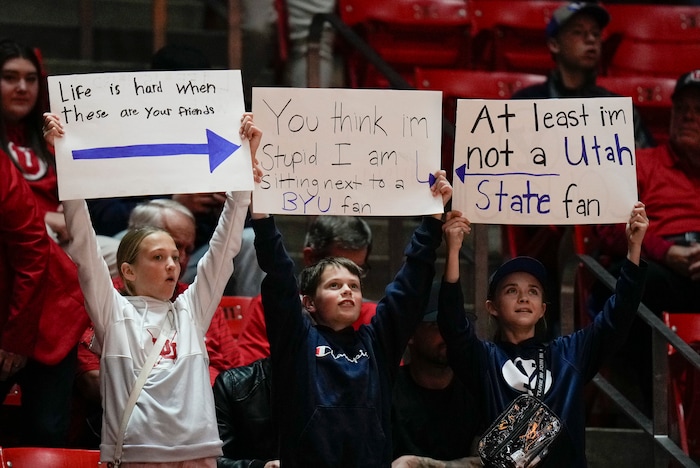 (Bethany Baker  |  The Salt Lake Tribune) Fans hold up signs ahead of the game between the Utah Utes and the Brigham Young Cougars at the Jon M. Huntsman Center in Salt Lake City on Saturday, Dec. 9, 2023.