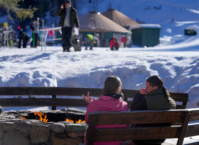 (Bethany Baker  |  The Salt Lake Tribune) Two people sit in front of an open fire at the bottom of a run at Sundance Resort near Provo on Thursday, Dec. 14, 2023.