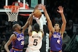 Utah Jazz forward Cody Williams (5) slips between Phoenix Suns forward Kevin Durant (35) and center Oso Ighodaro (4) to score during the second half of an NBA basketball game Saturday, Jan. 11, 2025, in Phoenix. (AP Photo/Ross D. Franklin)