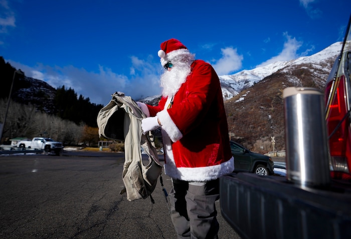 (Bethany Baker  |  The Salt Lake Tribune) Rudy Schenk, a fly fisherman dressed as Santa Claus, puts on his fishing vest in the parking lot at Vivian Park in Provo Canyon on Saturday, Dec. 23, 2023.