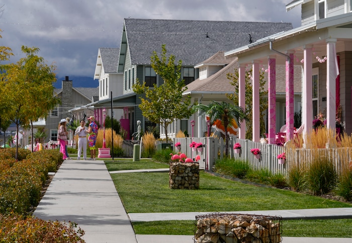 (Bethany Baker  |  The Salt Lake Tribune) People stand on a path between homes in a section of Daybreak that has collectively created a Barbieland-themed community for Halloween on Wednesday, Oct. 11, 2023.