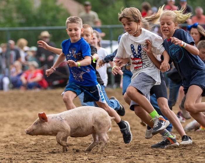 (Rick Egan | The Salt Lake Tribune) Kids wrestle for a pig, in the Pig Chase competition, during the Liberty Days Celebration in Liberty, Utah, on Tuesday, July 4, 2023.  The kids that catch the chickens get to keep them. 