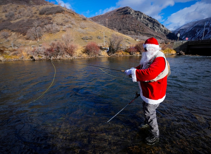 (Bethany Baker  |  The Salt Lake Tribune) Rudy Schenk, a fly fisherman dressed as Santa Claus, stands in the Provo River at Vivian Park in Provo Canyon on Saturday, Dec. 23, 2023.