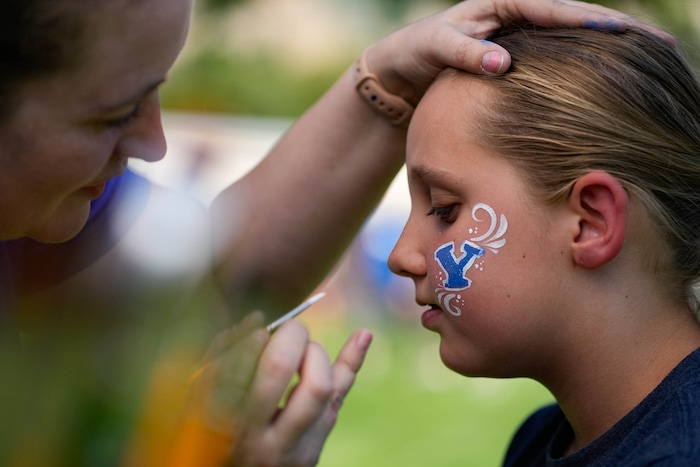 (Francisco Kjolseth | The Salt Lake Tribune) Ruby Fawcett, 10, gets her cheek painted by Kassie Voigt as BYU fans join the Big 12 Conference celebration on Saturday, July 1, 2023.