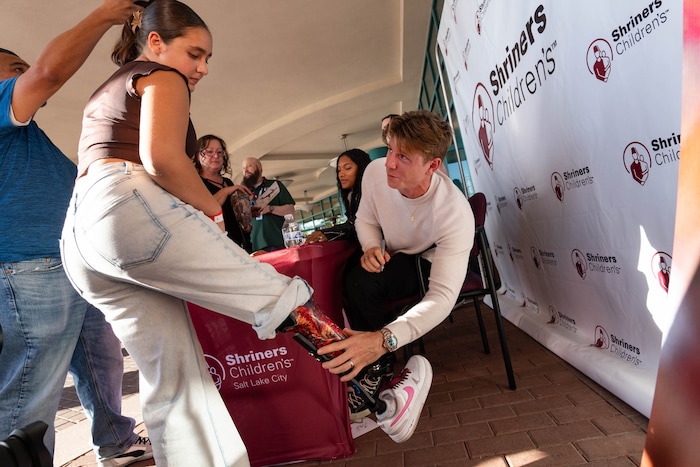 (Francisco Kjolseth  | The Salt Lake Tribune) Hunter Woodhall a gold medalist in the Paris 2024 Games, signs Brailey Partida’s prosthetic leg during a visit to Shriners Children’s Hospital, one of his first stops post Paralympic Games on Wednesday, Sept. 18, 2024. Woodhall had his legs amputated when he was 11 months old and spent much of his youth at the hospital.