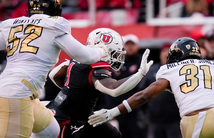 (Bethany Baker  |  The Salt Lake Tribune) Utah Utes running back Jaylon Glover (1) tries to avoid the tackle from Colorado Buffaloes defensive lineman Chazz Wallace (52) and Colorado Buffaloes safety Jaden Milliner-Jones (31) at Rice-Eccles Stadium in Salt Lake City on Saturday, Nov. 25, 2023.