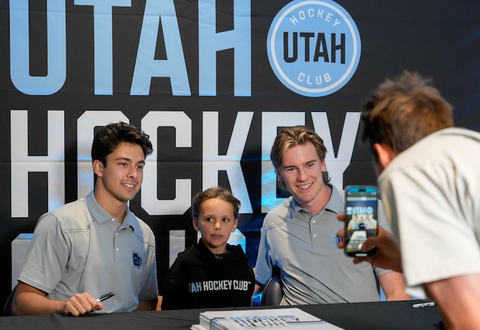 (Francisco Kjolseth  |  The Salt Lake Tribune) Miles Tews, 5, has his picture taken with Utah Hockey Club prospects Dylan Guenther and Josh Doan as the Utah Hockey Club hosts their first NHL draft party at the Delta Center on Friday, June 28, 2024.