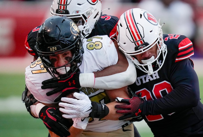 (Bethany Baker  |  The Salt Lake Tribune) Colorado Buffaloes tight end Michael Harrison (87) is tackled by Utah Utes linebacker Levani Damuni (3) and Utah Utes safety Sione Vaki (28) at Rice-Eccles Stadium in Salt Lake City on Saturday, Nov. 25, 2023.