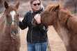 (Molly Wald | Best Friends Animal Society) Jen Reid, horse sanctuary manager at Best Friends Animal Society in Kanab, stands next to rescued horse Emma and cradles the head of Marina, Emma's daughter. Reid helped rescue the pair in June 2023, when they became stranded on a Lake Powell beach.