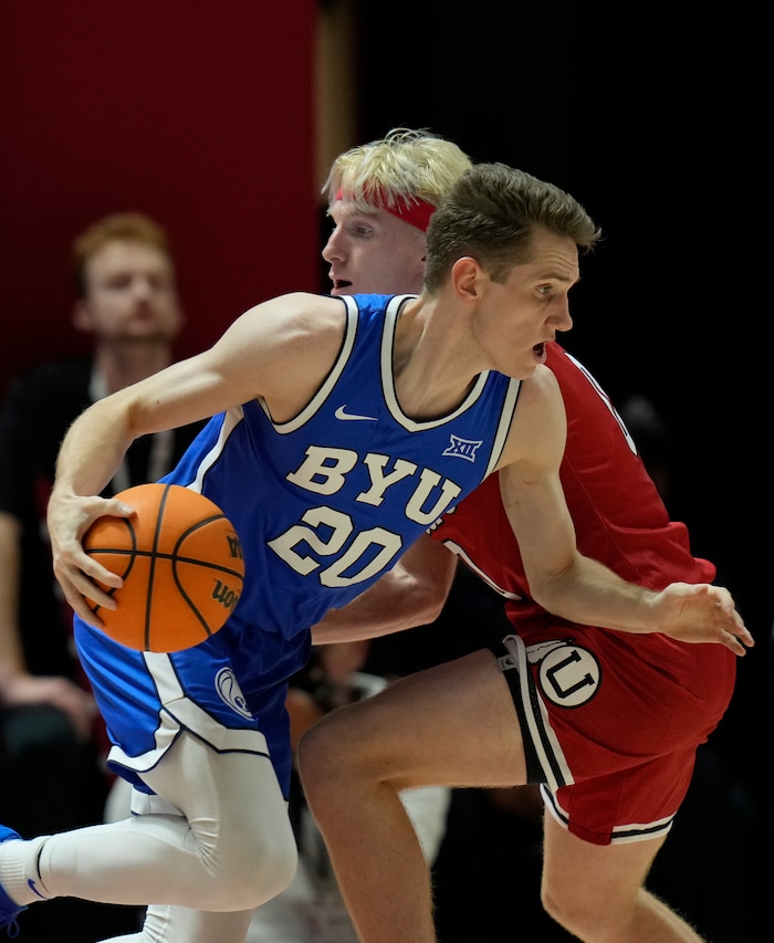 (Bethany Baker  |  The Salt Lake Tribune) Brigham Young Cougars guard Spencer Johnson (20) drives past Utah Utes guard Hunter Erickson (0) at the Jon M. Huntsman Center in Salt Lake City on Saturday, Dec. 9, 2023.