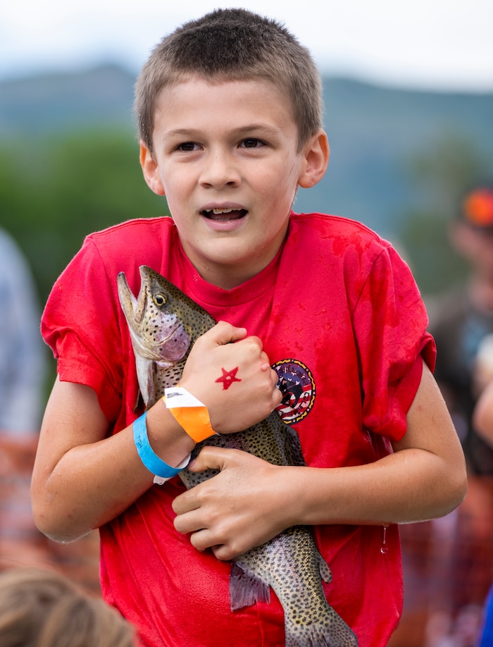 (Rick Egan | The Salt Lake Tribune)  Burke Ferrin, 9 grabs a trout during the Fish Catch, at the Liberty Days Celebration in Liberty, UT, on Tuesday, July 4, 2023.  