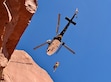 (Grand County Sheriff’s Search and Rescue) A rescuer is lowered from a helicopter toward Castleton Tower to reach an injured climber during a technical rescue operation led by Grand County Sheriff’s Search and Rescue.