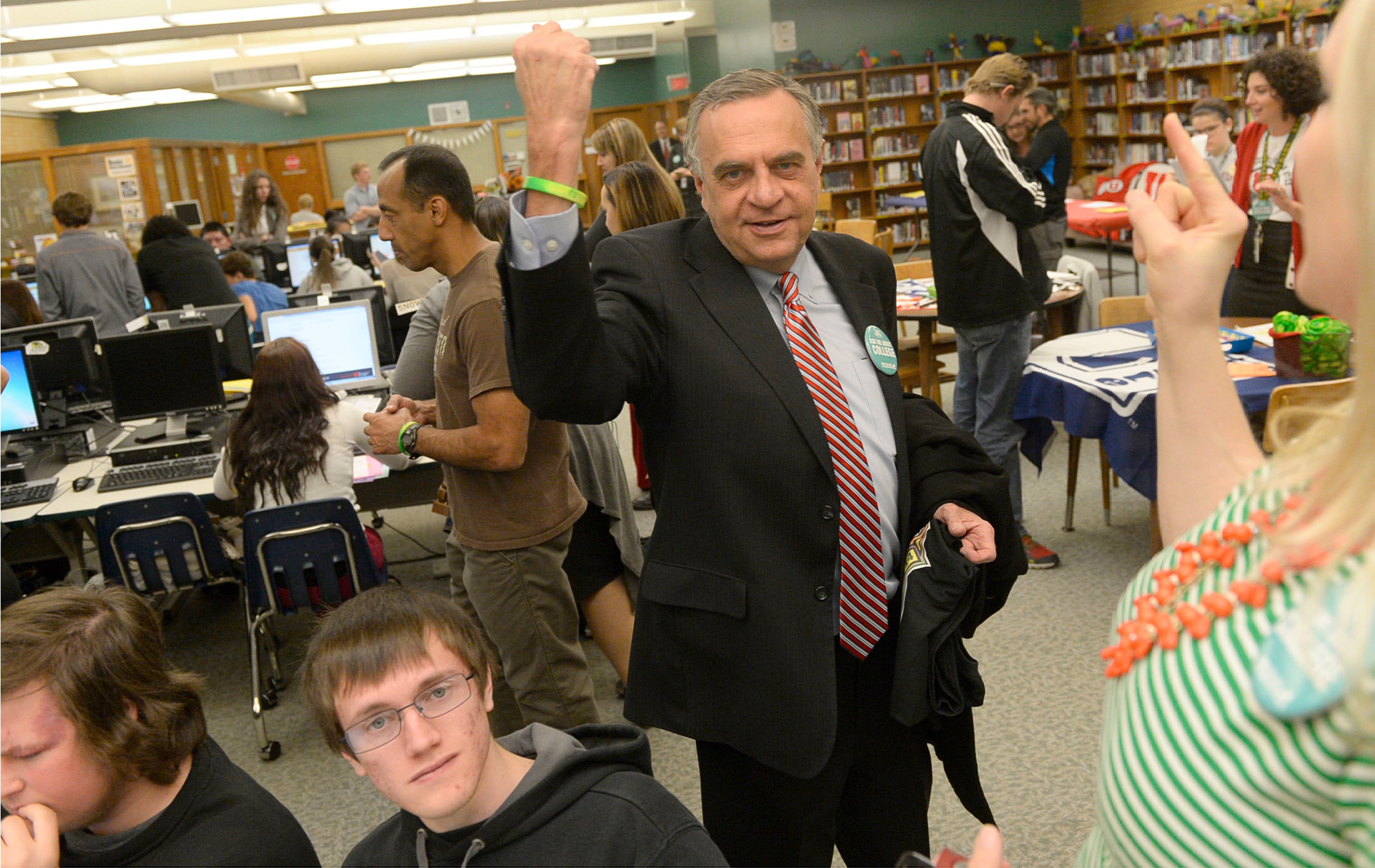 [Al Hartmann | The Salt Lake Tribune] Utah Commissioner of Higher Education Dave Buhler rises his arm to show the neon bracelet seniors wear after completing online college application Wednesday November 12 at Kearns High School. Thirty Kearns High School seniors applied for state colleges as party of Utah College Application Week.