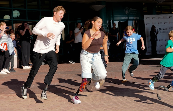 (Francisco Kjolseth  | The Salt Lake Tribune) Hunter Woodhall races alongside Brailey Partida, 13, as the Paralympic gold medalist returns to Shriners Children’s Hospital for a special visit following the Paris 2024 Games on Wednesday, Sept. 18, 2024. Woodhall had his legs amputated when he was 11 months old and spent much of his youth at the hospital.