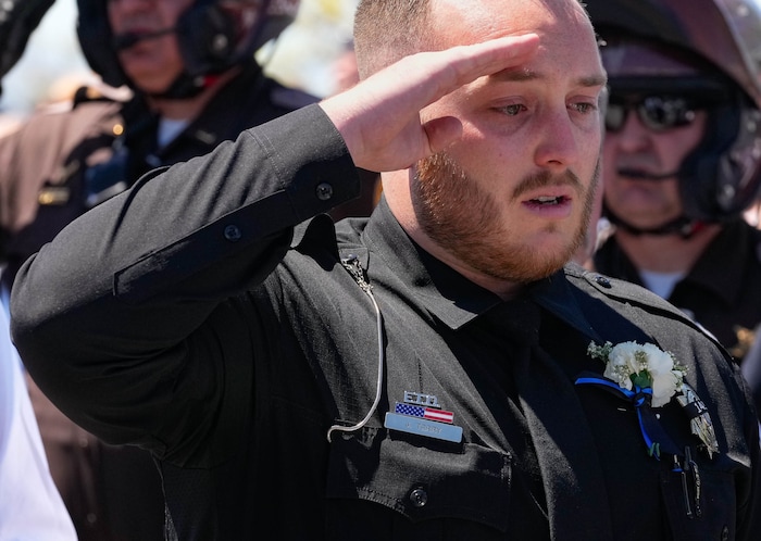 (Francisco Kjolseth  |  The Salt Lake Tribune) Officer Jake Terry salutes as the casket containing his father-in-law as it is placed in a hearse following funeral services for Santaquin police Sgt. Bill Hooser at the UCCU Center at Utah Valley University on Monday, May 13, 2024.