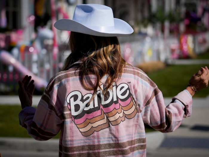 (Bethany Baker  |  The Salt Lake Tribune) Lori Remington, dressed as “Barn Barbie,” walks down a path between homes in a section of Daybreak that has collectively created a Barbieland-themed community for Halloween on Wednesday, Oct. 11, 2023.