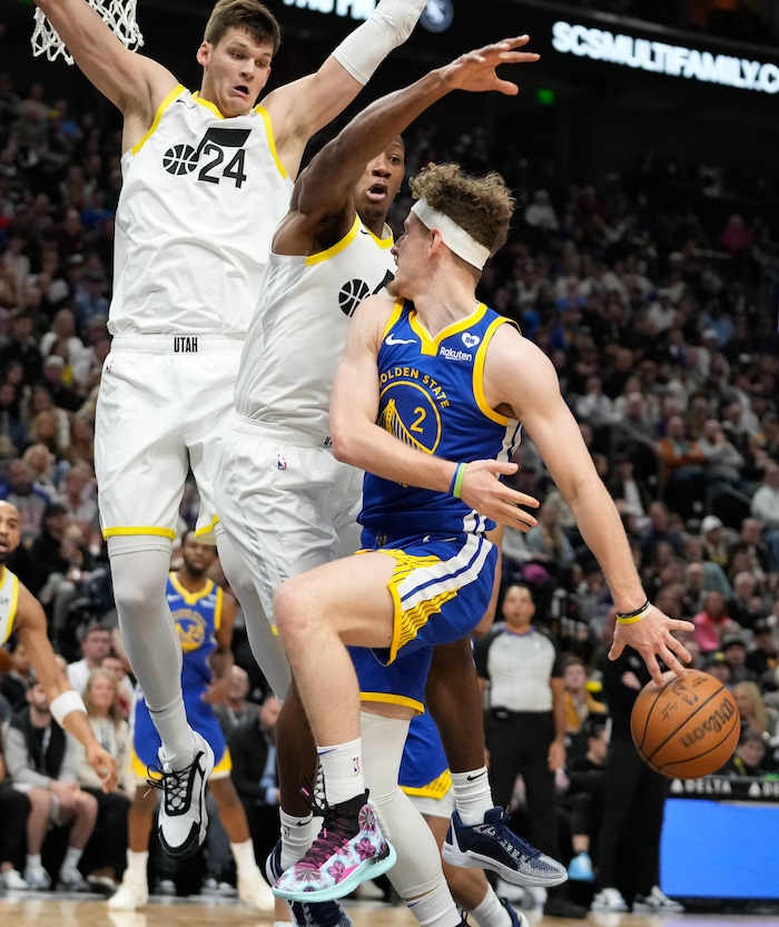 (Francisco Kjolseth  |  The Salt Lake Tribune) Golden State Warriors guard Brandin Podziemski (2) makes a pass behind his back while pressured by Utah Jazz center Walker Kessler (24) and Utah Jazz guard Kris Dunn (11) during an NBA basketball game Thursday, Feb. 15, 2024, in Salt Lake City.