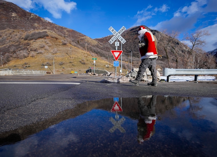 (Bethany Baker  |  The Salt Lake Tribune) Rudy Schenk, a fly fisherman dressed as Santa Claus, walks towards the Provo River at Vivian Park in Provo Canyon on Saturday, Dec. 23, 2023.