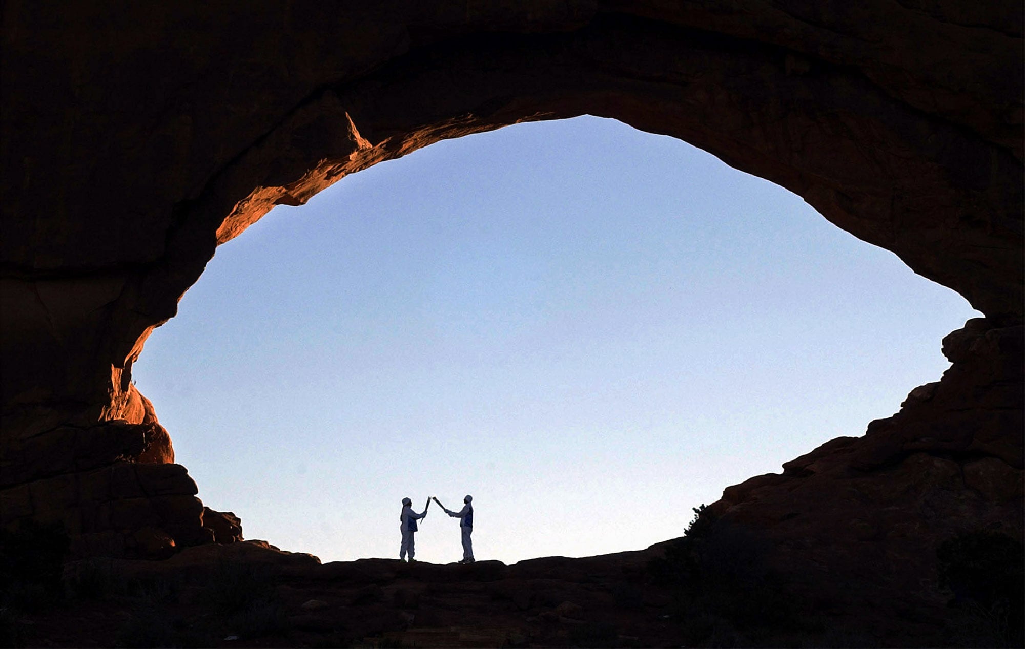 (Steve Griffin | The Salt Lake Tribune) Devan Lomayaoma, right, of Polacca, Ariz., lights the torch of Anne Wheelock Gonzales, of Santa Fe, N.M., as they stand under the North Window at Arches National Park, Monday, Feb. 4, 2002.