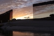 (Eugene Garcia | AP) A pair of migrant families from Brazil passes through a gap in the border wall to reach the United States after crossing from Mexico in Yuma, Ariz., to seek asylum on June 10, 2021.