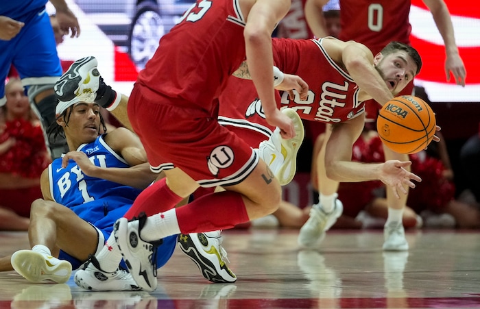 (Bethany Baker  |  The Salt Lake Tribune) Utah Utes guard Rollie Worster (25) passes the ball to Utah Utes guard Gabe Madsen (55) as Brigham Young Cougars guard Trey Stewart (1) falls at the Jon M. Huntsman Center in Salt Lake City on Saturday, Dec. 9, 2023.