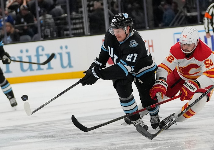 (Francisco Kjolseth  | The Salt Lake Tribune) Utah Hockey Club center Barrett Hayton (27) maneuvers the puck alongside Calgary Flames defenseman MacKenzie Weegar (52) during an NHL hockey game at the Delta Center in Salt Lake City on Wednesday, Oct. 30, 2024. Utah won 5-1.