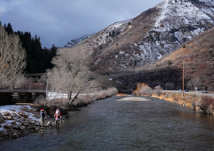 (Bethany Baker  |  The Salt Lake Tribune) Brett Prettyman stands with Rudy Schenk, a fly fisherman dressed as Santa Claus, beside the Provo River at Vivian Park in Provo Canyon on Saturday, Dec. 23, 2023.