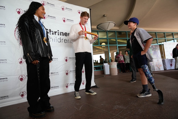 (Francisco Kjolseth  | The Salt Lake Tribune) Hunter Woodhall and Tara Davis-Woodhall, both gold medalists in the Paris 2024 Games, visit with Will MaCKay, 11, who got a signed track baton from Hunter when he was 3, as the Olympic/Paralympic athletes visit Shriners Children’s Hospital on Wednesday, Sept. 18, 2024. 