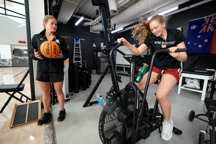 (Francisco Kjolseth  |  The Salt Lake Tribune) Lindsey Kirschman, Director of Women’s Basketball Sports Performance, left, runs Utah basketball player Gianna Kneepkens through a series of training drills, including multiple rounds on the assault bike, on Wednesday, Jan. 24, 2024. Kneepkens is making her way back to the court following a season-ending injury that left her with multiple broken bones in her foot. 