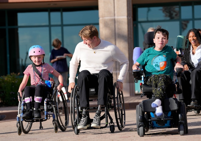 (Francisco Kjolseth  | The Salt Lake Tribune) Hunter Woodhall, a gold medalist in the Paris 2024 Paralympic Games, races Madi Sandstrom, left, and Drew Cheever during a visit to Shriners Children’s Hospital on Wednesday, Sept. 18, 2024. Woodhall had his legs amputated when he was 11 months old and spent much of his youth at the hospital.