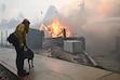 (Nic Coury | AP) A firefighter pets a dog while battling a fire in Altadena, California. About 1,000 Latter-day Saints have been displaced by flames.