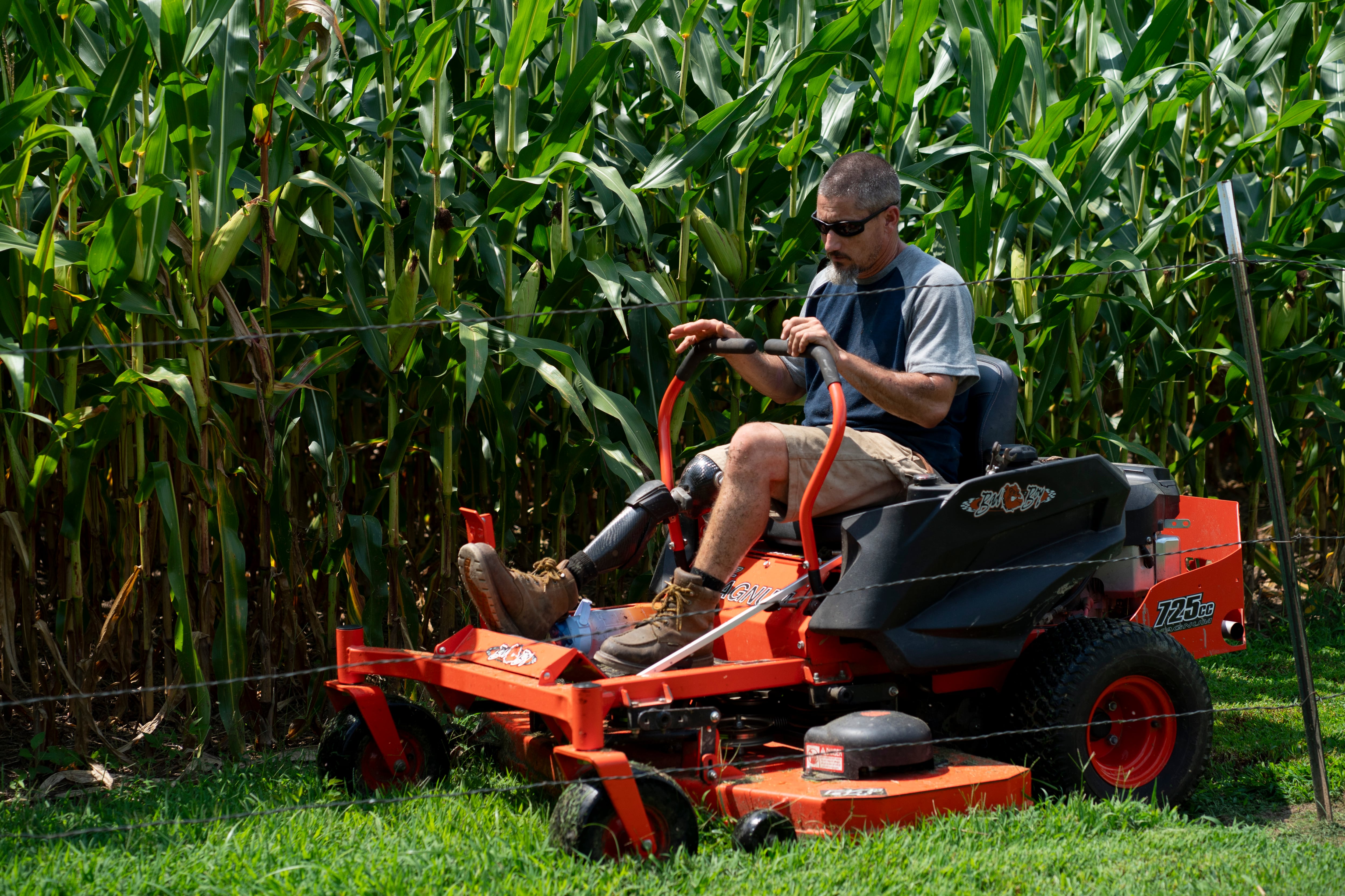 (Denny Simmons | The Tennessean) Scott Restivo finishes up the mowing of his family's rental property in Cedar Hill, Tenn., Tuesday, July 30, 2024. Restivo, a disabled U.S. Army veteran now uses a prosthetic leg in place of the one he lost after a life-threatening infection in 2018. He did three tours of duty in Iraq and Afghanistan and was injured in a guard tower rocket attack in 2012.