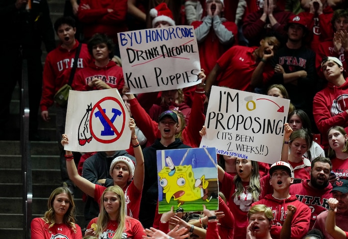 (Bethany Baker  |  The Salt Lake Tribune) Utah Utes fans hold up signs during the game against the Brigham Young Cougars at the Jon M. Huntsman Center in Salt Lake City on Saturday, Dec. 9, 2023.