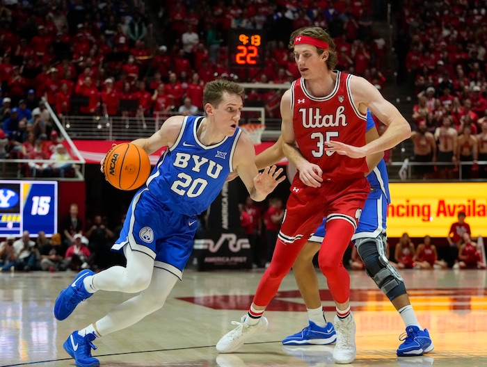 (Bethany Baker  |  The Salt Lake Tribune) Brigham Young Cougars guard Spencer Johnson (20) drives to the basket as he is defended by Utah Utes center Branden Carlson (35) at the Jon M. Huntsman Center in Salt Lake City on Saturday, Dec. 9, 2023.