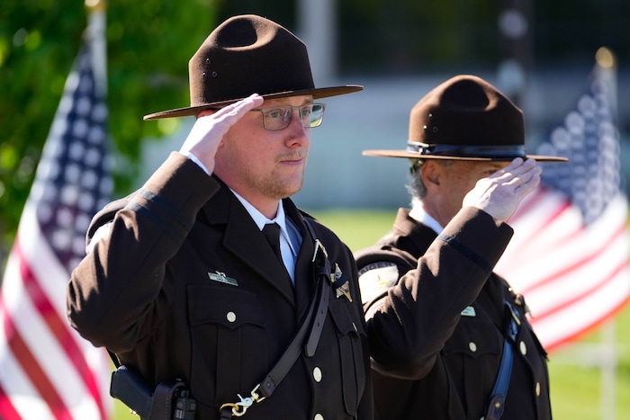 (Francisco Kjolseth  |  The Salt Lake Tribune) Officers salute the arrival of the hearse containing the body of Santaquin police Sgt. Bill Hooser at the UCCU Center at Utah Valley University on Monday, May 13, 2024.