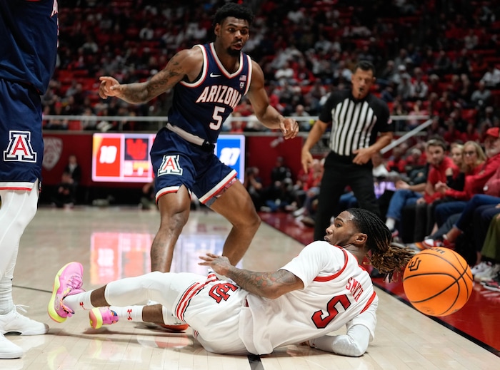 (Francisco Kjolseth  |  The Salt Lake Tribune) Utah Utes guard Deivon Smith (5) is tripped up while Arizona Wildcats guard KJ Lewis (5) looks on in PAC-12 basketball action between the Utah Utes and the the Arizona Wildcats at the Jon M. Huntsman Center, on Thursday, Feb. 8, 2024.