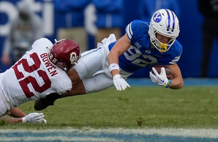 (Bethany Baker  |  The Salt Lake Tribune) Oklahoma Sooners defensive back Peyton Bowen (22) tackles Brigham Young Cougars wide receiver Parker Kingston (82) at LaVell Edwards Stadium in Provo on Saturday, Nov. 18, 2023.