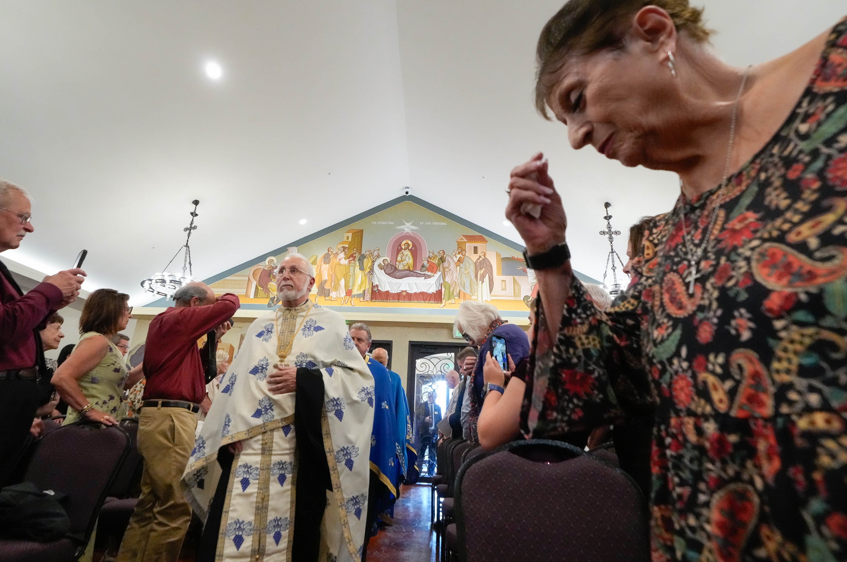 (Francisco Kjolseth | The Salt Lake Tribune) Father Constantine Zozos of Pocatello Idaho walks through the new St. Anna Greek Orthodox Church in Sandy as Dena Savos forms the cross on herself during opening services on Saturday, July 13, 2024, in the new church that was transformed from a garden center into a sacred sanctuary.