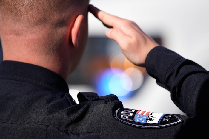 (Francisco Kjolseth  |  The Salt Lake Tribune) Officers salute the arrival of the hearse containing the body of Santaquin police Sgt. Bill Hooser at the UCCU Center at Utah Valley University on Monday, May 13, 2024.