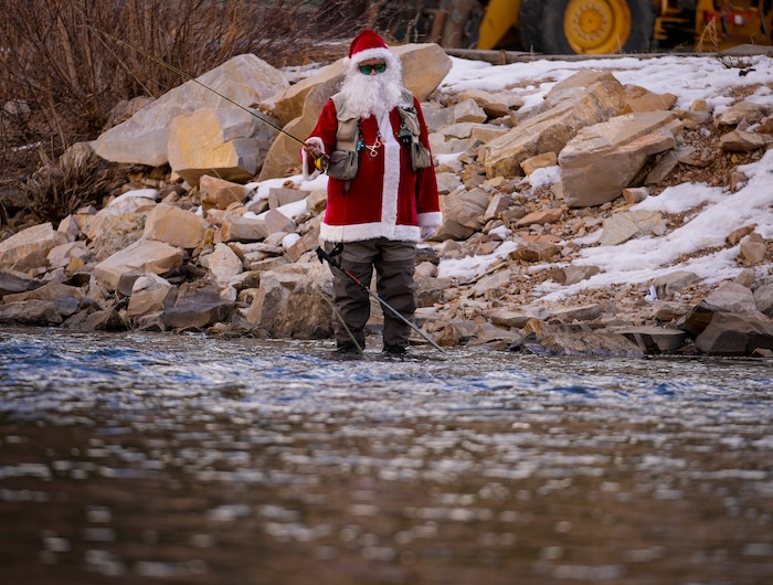 (Bethany Baker  |  The Salt Lake Tribune) Rudy Schenk, a fly fisherman dressed as Santa Claus, stands in the Provo River at Vivian Park in Provo Canyon on Saturday, Dec. 23, 2023.